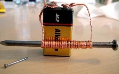A battery connected to a wire that wraps around a nail.