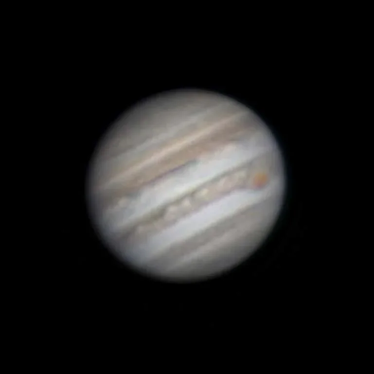 A photograph of Jupiter taken with a land-based amateur telescope shows details of the Great Red Spot and other storm bands.