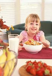 A photograph shows a girl at a table with a bowl of flaked cereal.
