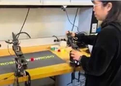 A photo showing a teacher teleoperating the SO-101 arm leader at the AI lab.