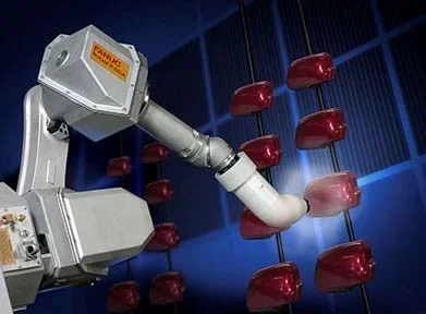 A robotic arm applies spray paint on a car’s headrest.