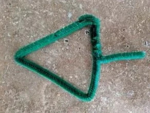 A green pipe cleaner is shown shaped in the form of an arrow.