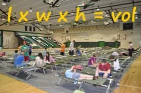 A photograph shows people sitting on rows of cots in a high school gymnasium. Text over the photo: l x w x h = vol.