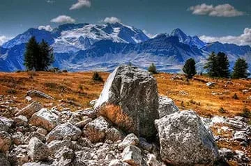 Two images: A photo shows large boulders in a foreground valley with a mountain backdrop.