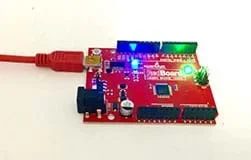 A photograph shows a red circuit board with illuminated blue and green LEDs and a USB cable.