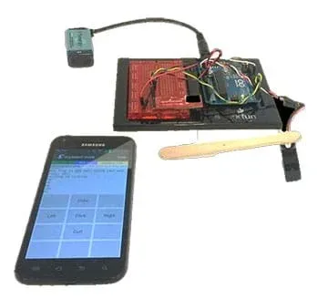 A photograph shows a cell phone open to an application that controls a nearby servo using a Bluetooth module and an Arduino Uno.
