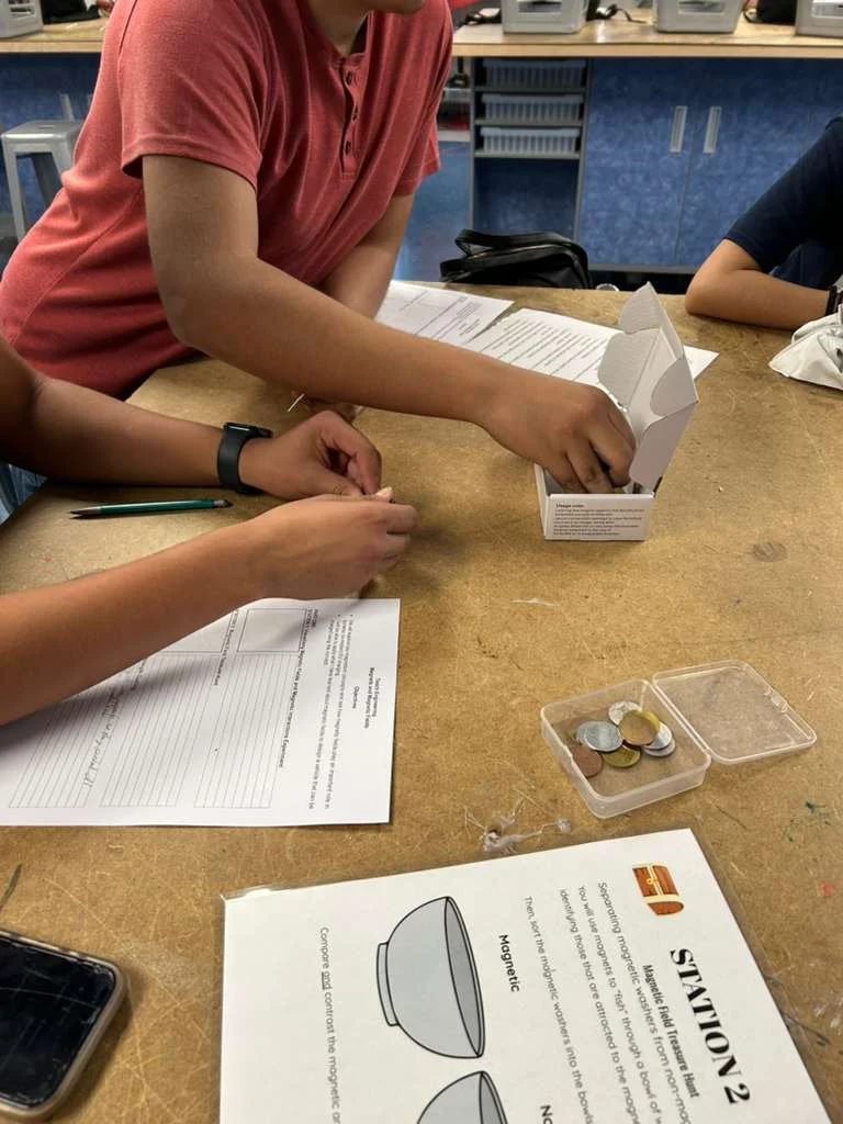 A photo showing students testing different materials with magnets to identify whether the objects are magnetic or not.