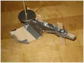 Photo shows a rudimentary model plow made from thin pieces of wood and duct tape.