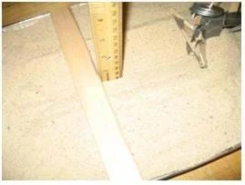 Photo shows a ruler placed vertically into the bottom of the furrow next to another ruler placed across the pan of sand, resting on the pan edges, providing a consistent level to which the depth can be measured.