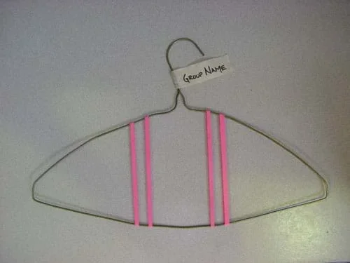 Photograph of a wire hanger with four rubber bands stretched across its top and bottom wires, with a masking tape tag on the hook, labeled with the group name.