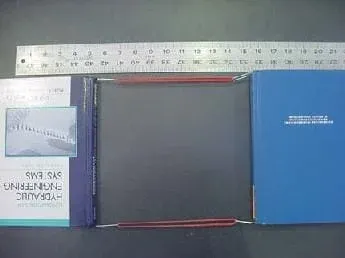 A photo shows two books attached together with a sling-type setup made with rubber bands and paperclips. A ruler is in place to measure the movement of the books before and after the books are pulled apart.