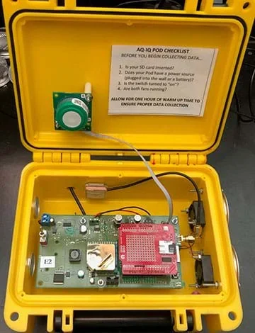 Three photographs show three items placed right under the same short metal pipe that pokes out from a black case (inlet to the Pod air quality monitor). The items are a votive candle, plastic bottle of rubbing alcohol and a burning wooden coffee stir stick with a flame.