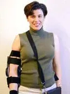 Photo shows a woman with a support structured strapped to her left arm and a messenger-type bag hanging across her torso.