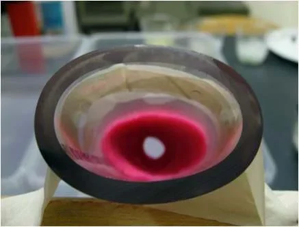 Photo looking into the end of a piece of plastic tubing shows it almost completely blocked by red material, except for a small opening.