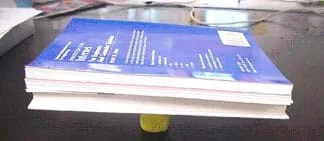 Photo shows three books balancing on a piece of clay.