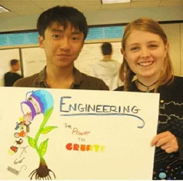 Two teens hold a poster they made that says, "Engineering – the power to create."