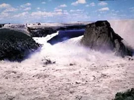 Photo shows water gushing through a break in the wall of a dam.