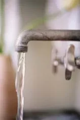 Photo shows a pipe faucet with a clear stream of water coming from it.