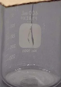 A photograph showing the silver foil rectangle folded in half and hanging on a hook suspended into a jar.
