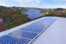 A photograph showing bright light reflecting off of a solar panel that is composed of many iridescent blue photovoltaic cells connected together in rectangular panels.