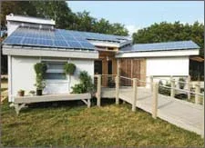 Photo of a small, modern home with photovoltaic panels on its angled rooftop.