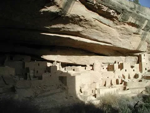 A photograph shows stone structures under a protective rock cliff.