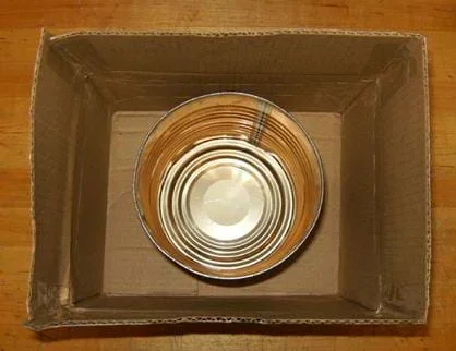 A photo looking down into a cardboard box with an open metal coffee can placed at the bottom.