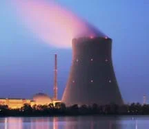 Photo shows glow of lights and emissions of a tall and wide nuclear power plant tower.
