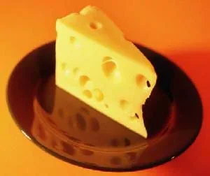 A photograph of a wedge of Swiss cheese on a brown plate.