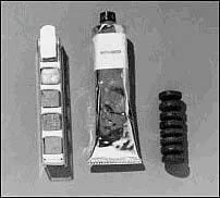 Photo shows three items. The tube looks like a toothpaste tube, and one of the snacks looks like a small stack of eight mini-car tires. The other snack appears to be a set of small cubes placed in a metal holder.