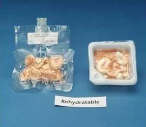 Photo shows two different packages of rehydratable shrimp cocktail. The package on the left is clear and vacuum sealed, and has a short tube placed in the side for adding water. The package on the right is a translucent plastic square box, with the lid removed. A sign below the packages reads: "Rehydratable."
