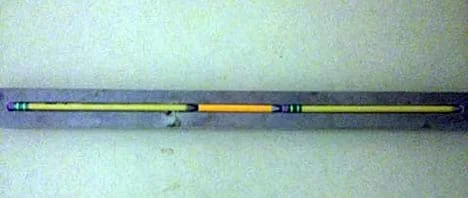 A photograph shows three pencils, lined up in a piece of wood with a groove cut down the middle of it, as a tray.