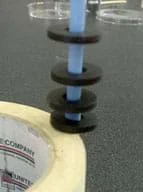 Photo of four ring magnets hovering above and below each other along the length of a vertical blue pencil.
