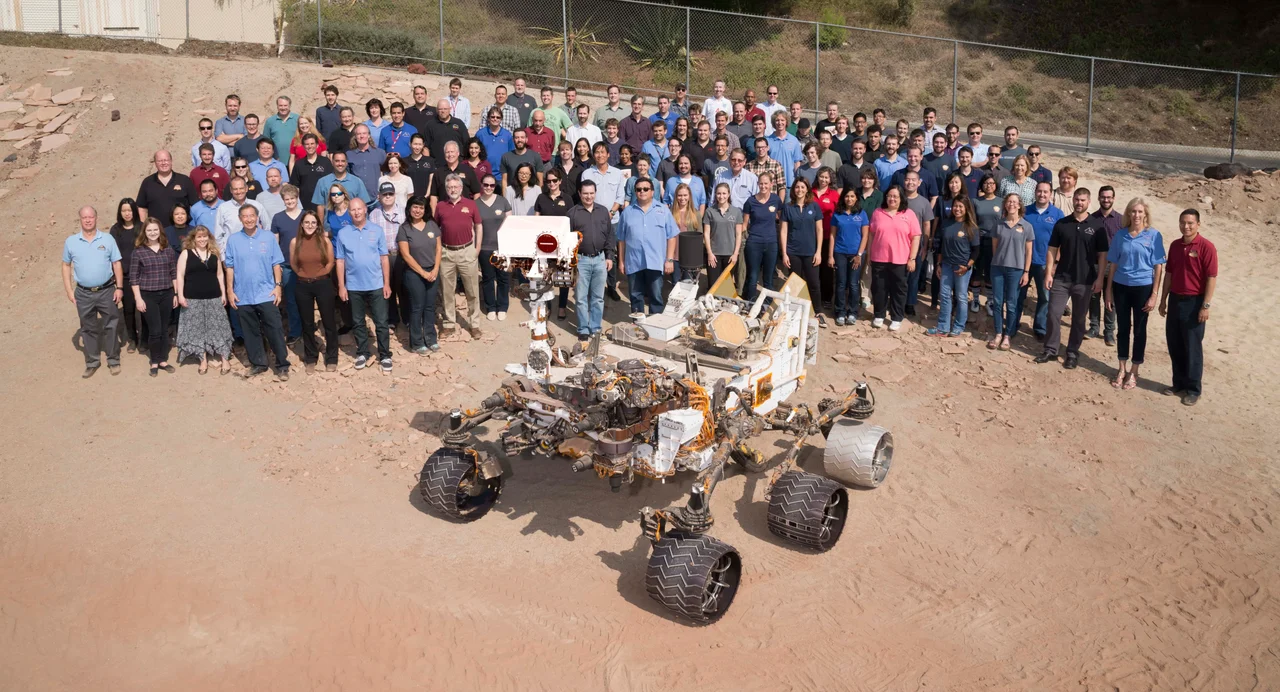 Mars rover model of Curiosity with its team