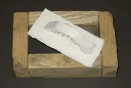Photo shows a rectangle made from nailed pieces of wood, and a board with a handle, sized to match the wooden rectangle interior opening.