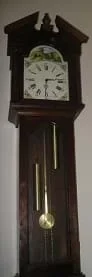 A grandfather clock with a rod pendulum swinging below the clock face.