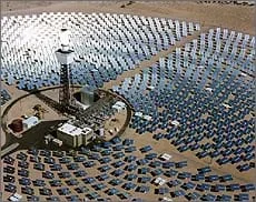 Photo shows a field of mirrors reflecting the sun towards a central tower.