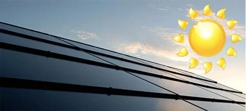 Sunlight reflects off sheets of shiny dark blue photovoltaic panels covering a rooftop.