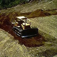 Photograph of a bulldozer pushing piles of soil.