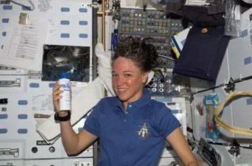 Photo shows a woman with messed hair holding a towel in front of a panel of instruments.