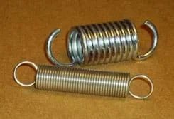 Photo shows two tension springs: a short and wide one made of thick metal and a longer, thinner one made of much thinner metal.