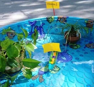 Photo shows a model Viking ship sailing toward a "finish" sign, all within a plastic backyard swimming pool.