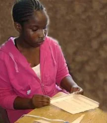 Photo shows a girl gluing together Popsicle sticks into a flat plane.