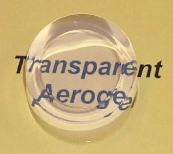 A photograph shows a transparent hockey puck-sized disk—an aerogel sample.