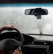 Photo shows rain on windshield, obscuring the view of the road ahead.