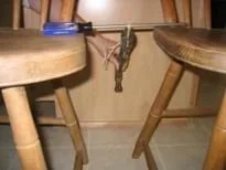 Photo shows a hammer suspended upside down by string from a long screwdriver bridged between two chair seats.