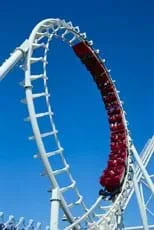 A photograph shows people sitting in a chain of carts going through a full loop on a roller coaster.
