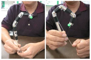 Side-by-side photos of a person demonstrating a functioning model finger, with the finger relaxed on the left and flexed through string tension on the right.