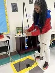 A photo showing a teacher attaching her shower clock prototype to a stand prior to testing.