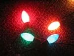 Four illuminated and different colored Christmas light bulbs.